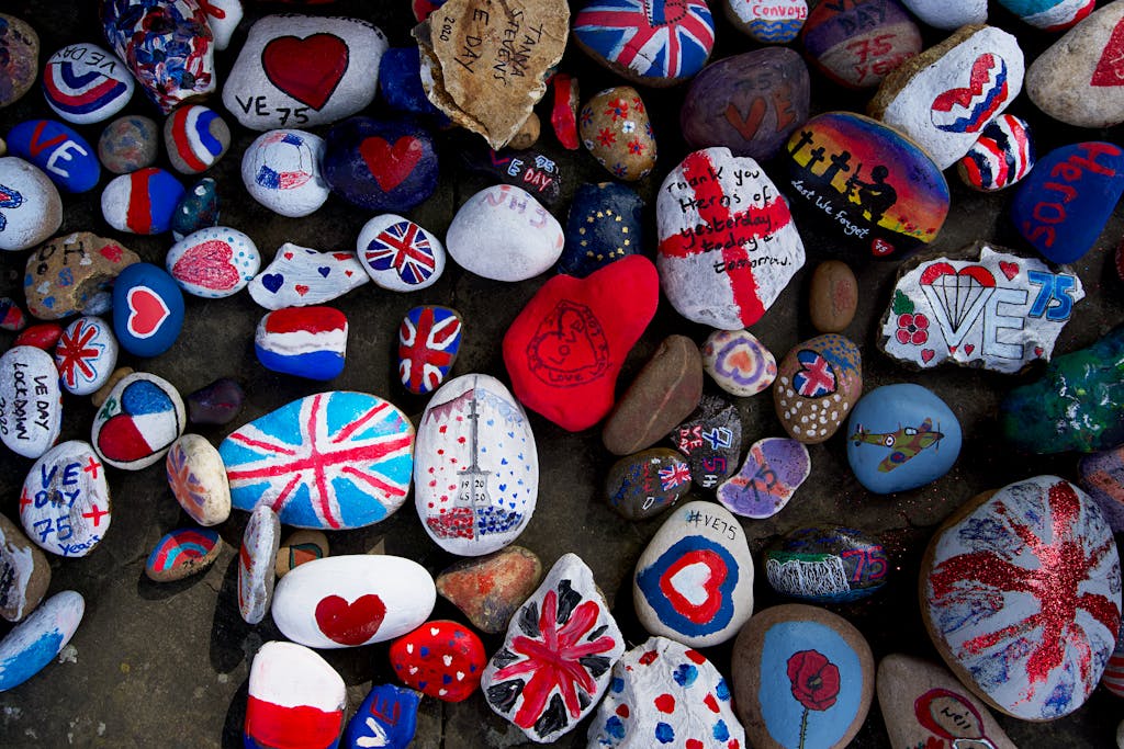 Vibrant hand-painted stones featuring Union Jack and hearts celebrating VE Day in England.